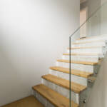 Concrete and wooden stairs with glass balustrade in modern minimalist interior